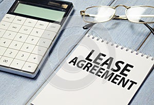 Text LEASE AGREEMENT on sticker with calculator, business concept