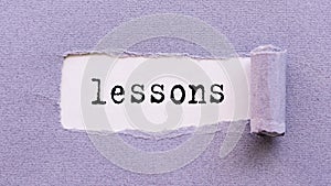 The text LESSONS appears on torn lilac paper against a white background