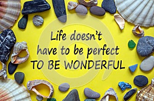 Text `life doesn`t have to be perfect to be wonderful` on a beautiful yellow background. Sea stones and seashells. Concept