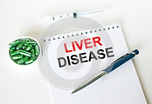 Text Liver Disease written in a notebook with a blue pen and a bunch of pills