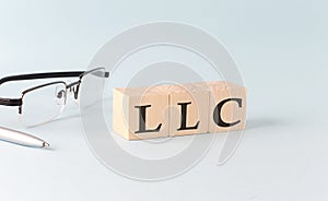 Text LLC - written on the wooden cubes on blue background