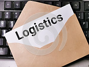 Text LOGISTICS written on white paper note in the envelope on computer keyboard.