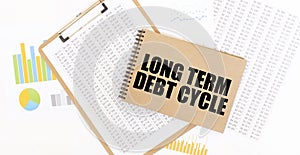 Text LONG TERM DEBT CYCLE on brown paper notepad on the table with diagram. Business concept