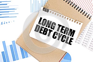 Text LONG TERM DEBT CYCLE on white paper sheet and brown paper notepad on the table with diagram. Business concept