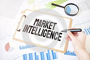Text Market Intelligence on white paper sheet and marker on businessman hand on the diagram. Business concept