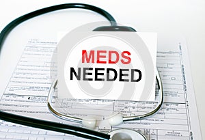 Text Meds Needed on the white card with the stethoscope and medical documents