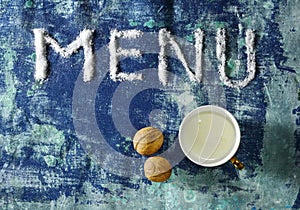 Text menu made of salt with cup of milk, walnuts isolated on grungy blue background