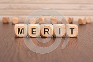 the text 'MERIT' is written on wooden cubes on a brown background