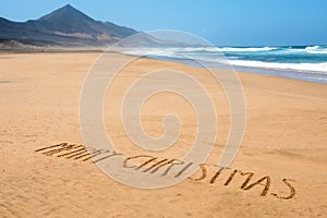 Text merry christmas in the sand of a beach