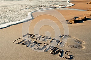 Text merry christmas in the sand of a beach