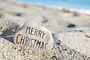 Text merry christmas in a stone on the beach