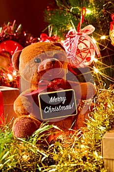 text merry christmas, teddy bear and gifts under a christmas tree