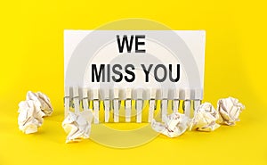 Text WE MISS YOU on the white short note paper yellow background