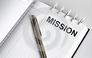 Text MISSION on the short note texture background with pen
