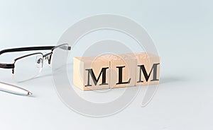 Text MLM written on the wooden cubes on blue background