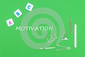 Text motivation, from above wooden minitures school supplies and abc letters on green background