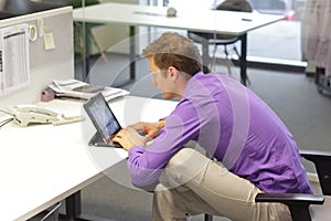 Text neck - man in slouching position  working with tablet at desk