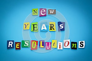 Text - New year`s resolutions. Cut colorful letters on blue background. Writing on banner, card. Inscription, message on poster.