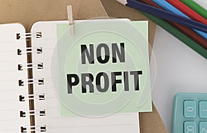 Text NON PROFIT on stickers. Clipboard with charts, pen, piggy bank and calculator on blue background.