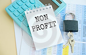 Text NON PROFIT on stickers. Clipboard with charts, pen, piggy bank and calculator on blue background. Accounting concept