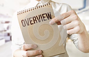 Text Overview on brown paper notepad in businessman hands in office. Business concept