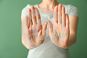 Text PANIC ATTACK and CALM written on woman's palms, closeup