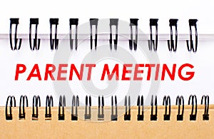 Text PARENT MEETING on white paper between white and brown spiral notepads