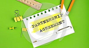 Text PARTNERSHIP AGREEMENT sign showing on green background with office tools