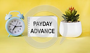 Text PAYDAY ADVANCE on notepad with clock and cactus on yellow background