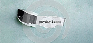 The text payday loans appearing behind torn green paper