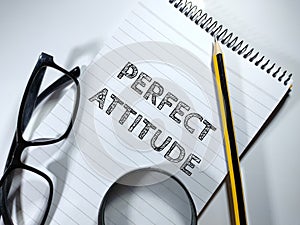 Text PERFECT ATTITUDE on notebook with pen,glaases and magnifying glass on white background. photo