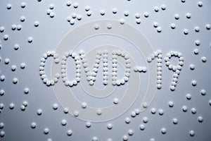 Text phrase Covid-19 sign concept made from white tablets