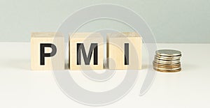 Text PMI on wood cube with gold coins on the