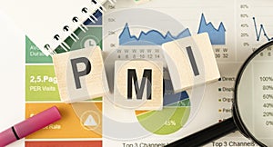 Text PMI on wood cube and gold pen lay on chart candle document paper photo