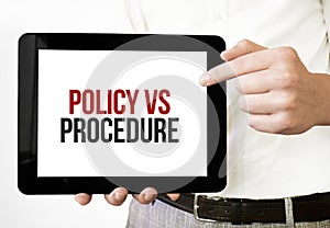 Text POLICY VS PROCEDURE on tablet display in businessman hands on the white bakcground. Business concept