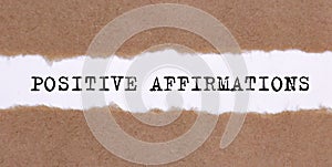 The text POSITIVE AFFIRMATIONS appearing behind torn paper. business photo
