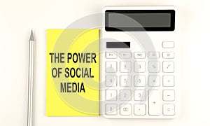 Text THE POWER OF SOCIAL MEDIA on yellow sticker, next to pen and calculator