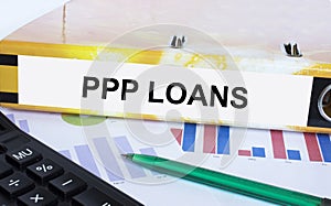 Text PPP Loans on the folder that is located on the financial diagrams with green pen and calculator