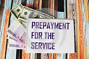 Text PREPAYMENT PAYMENT FOR SERVICE on a laptop, next to euro and dollar bills