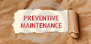 Text - Preventive Maintenance - appearing behind torn brown paper