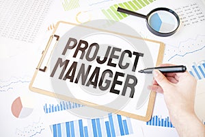 Text PROJECT MANAGER on white paper sheet and marker on businessman hand on the diagram. Business concept