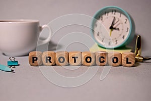Text PROTOCOL is written on a folder lying on a stack of papers with a pen on the table.