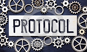 Text PROTOCOL is written on a folder lying on a stack of papers with a pen on the table