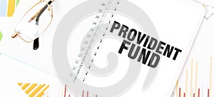 Text PROVIDENT FUND on white notepad, glasses, graphs and diagrams