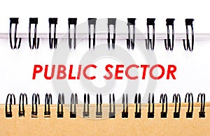 Text PUBLIC SECTOR on white paper between white and brown spiral notepads