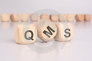 text 'QMS' - Quality Management System - on wooden cubes