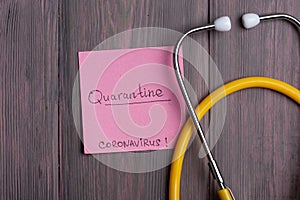 Text quarantine Coronavirus on sticky note and stethoscope on wooden background