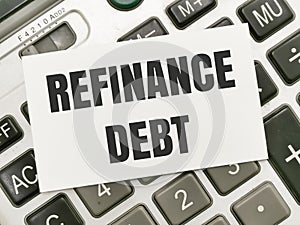 Text REFINANCE DEBT written on white paper note on calculator. photo