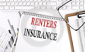Text RENTERS INSURANCE on Office desk table with keyboard, notepad and analysis chart on white background