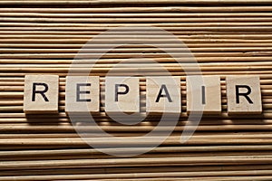 Text of REPAIR on wood abc cubes at wooden background